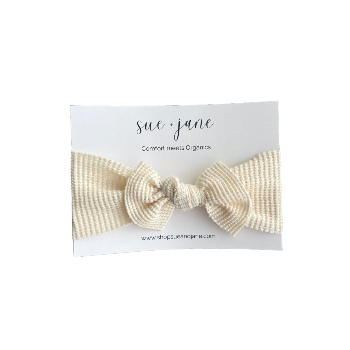 Three baby headbands with bows, displayed on a woven mat. Each headband is in a different shade of beige, ranging from light to medium.